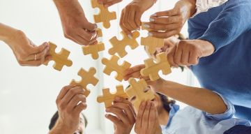 Angebot - Unternehmen - Teamsupervision - Team hält Puzzleteile in Händen